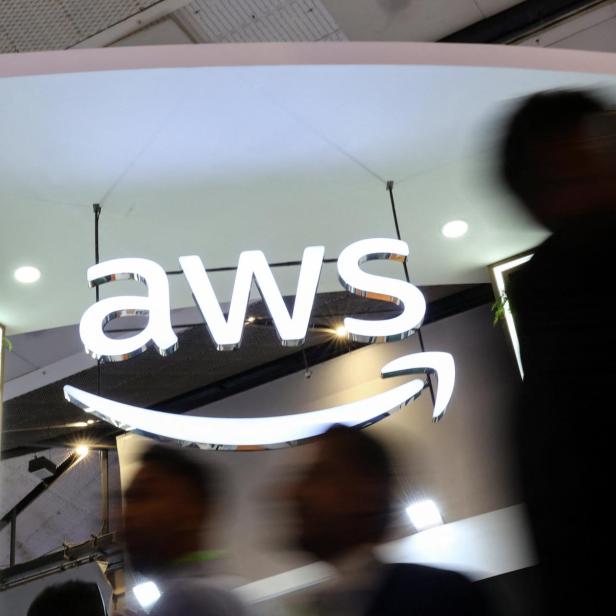 Das beleuchtete AWS-Logo hängt über einem Stand mit Pflanzen und unscharfen Personen.