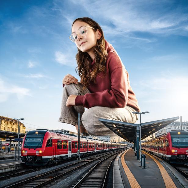 eine junge Frau hockt zwischen zwei Zügen 