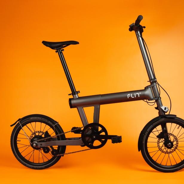 das Flit M2 Faltrad in grau und schwarz vor orangem Hintergrund