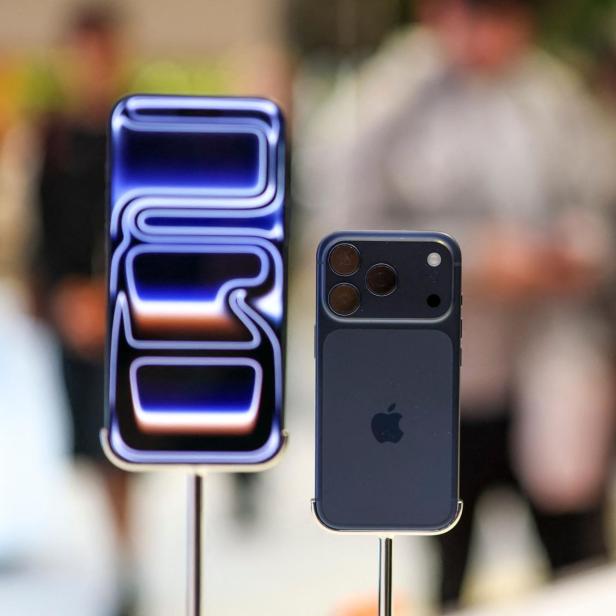 Mehrere neue Smartphones mit auffälligen Kameras und leuchtenden Displays stehen nebeneinander auf Ständern.