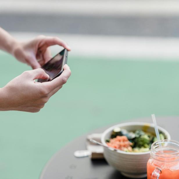 Eine Person macht ihrem Smartphone ein Foto von einer Mahlzeit