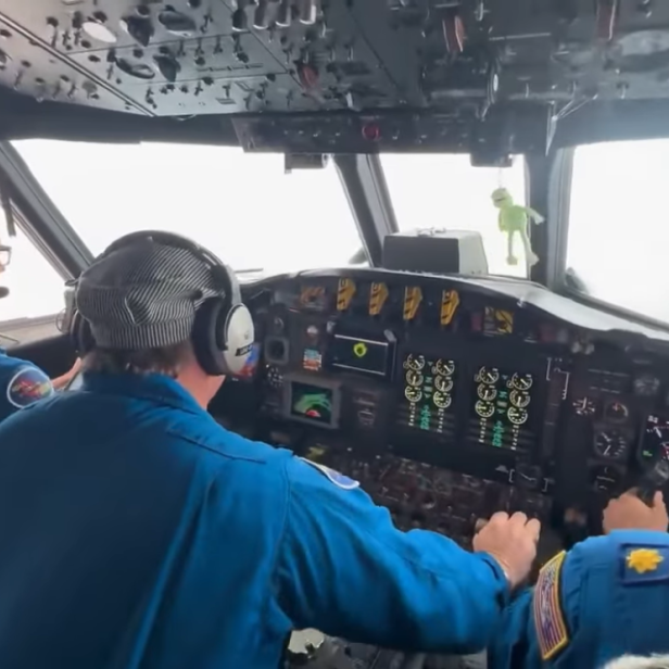 NOAA-Pilotenteam steuert die Lockheed WP-3D Orion durch das Auge des Hurrikans Melissa, während eine Kermit-Figur im Cockpit hängt.