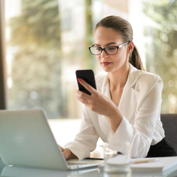 Eine Frau schaut während der Arbeit auf ihr Smartphone.