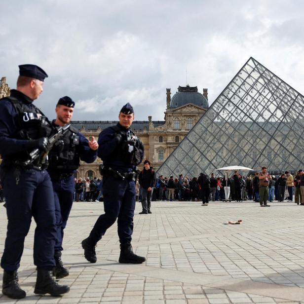Bewaffnete Polizisten patrouillieren vor der Glaspyramide des Louvre in Paris.