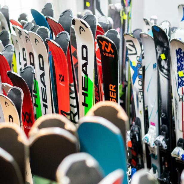 Viele gebrauchte Ski verschiedener Marken stehen dicht nebeneinander in einem Raum.