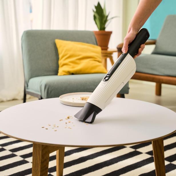 Kobold Handstaubsauger saugt Brösel am Beistelltisch auf 