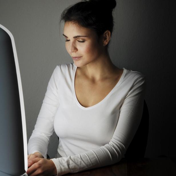 Eine Frau, die vor einer Tageslichtlampe sitzt 