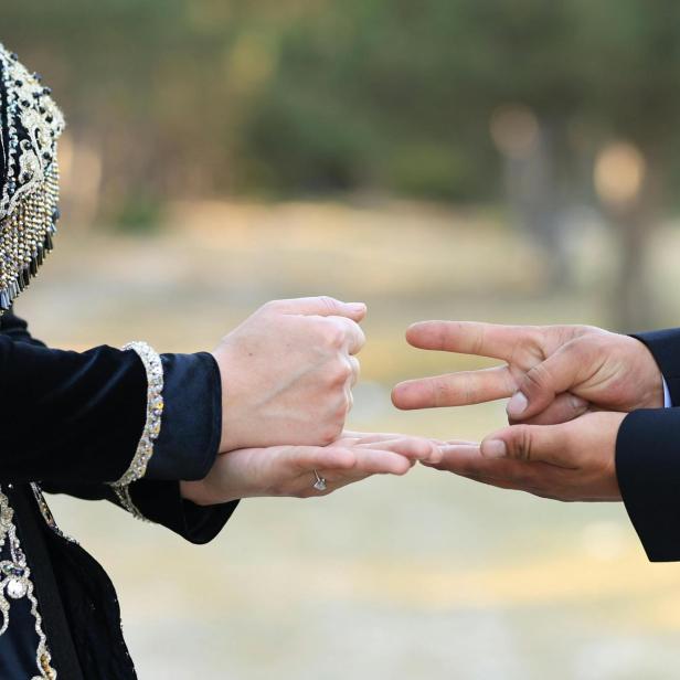 zwei Menschen spielen Schere Stein Papier, die linke Person zeigt Stein, die rechte Schere