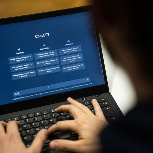 ein Laptop auf dem ChatGPT geöffnet ist, eine Person sitzt davor 