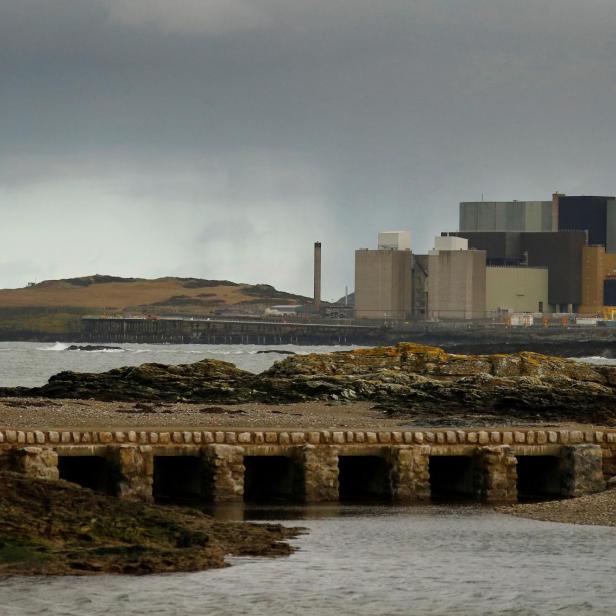 das ehem. Atomkrafwerk Wylfa an der Küste, grauer Himmel, Frau mit Hund