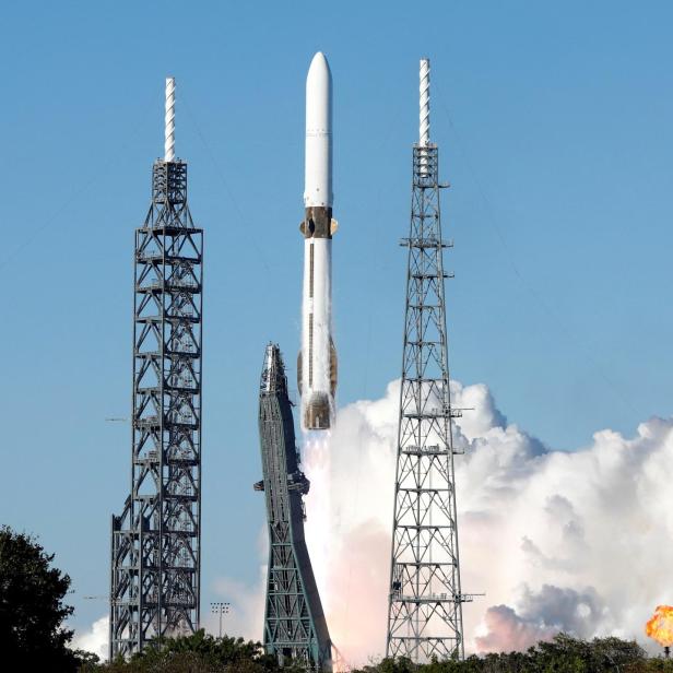 Eine Rakete startet zwischen zwei Starttürmen mit Rauch und Flammen in den Himmel.