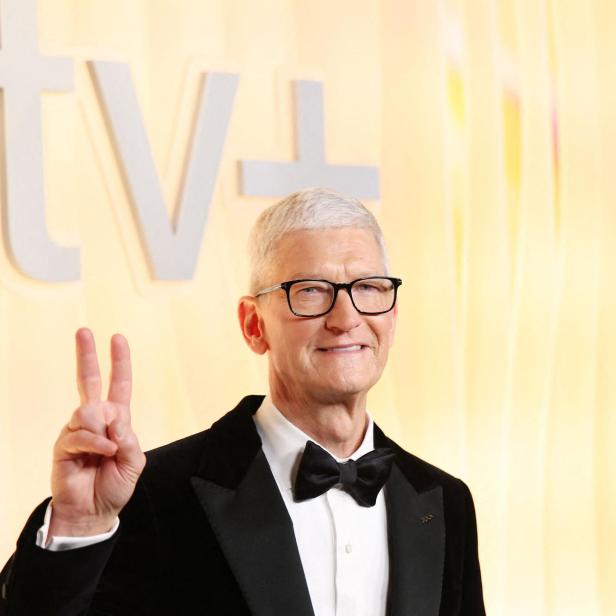 Tim Cook im Smoking zeigt das Victory-Zeichen vor einem Apple TV+-Logo.