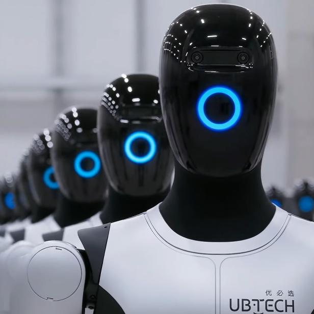 Mehrere Walker S2 Roboter von Ubtech Robotics stehen in einer Halle in Reih und Glied.