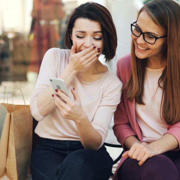 2 Frauen schauen auf das Smartphone und lachen 