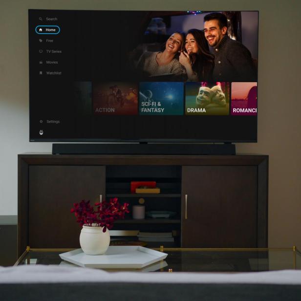 Ein moderner Fernseher mit TiVo-Oberfläche zeigt verschiedene Film- und Serienkategorien in einem gemütlichen Wohnzimmer.