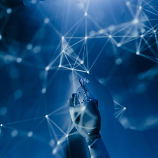 Eine Roboterhand zeigt auf ein leuchtendes, vernetztes digitales Netzwerk auf blauem Hintergrund.