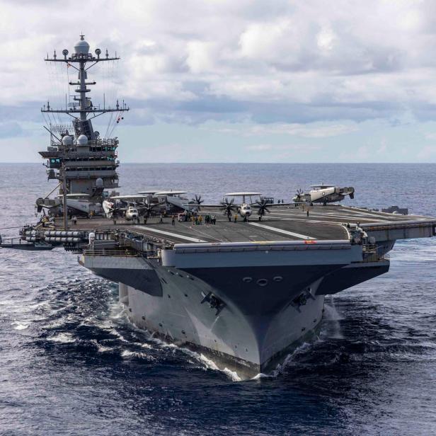 Flugzeugträger mit mehreren Flugzeugen auf dem Deck fährt durch das offene Meer.