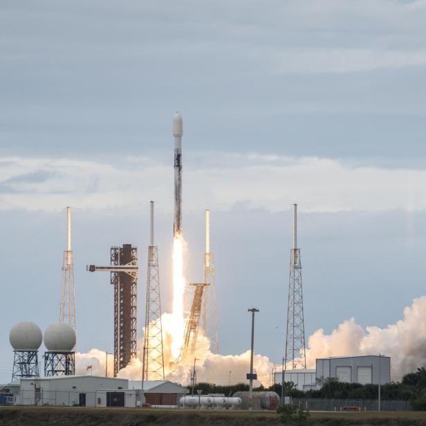 Eine Rakete startet mit hellem Feuer und Rauch von einer Startrampe in den Himmel.