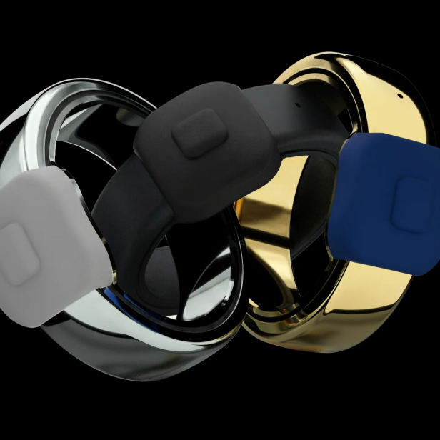 Drei Pebble Index 01 Ringe in Silber, Schwarz und Gold mit jeweils einem großen Knopf sind nebeneinander vor schwarzem Hintergrund zu sehen.