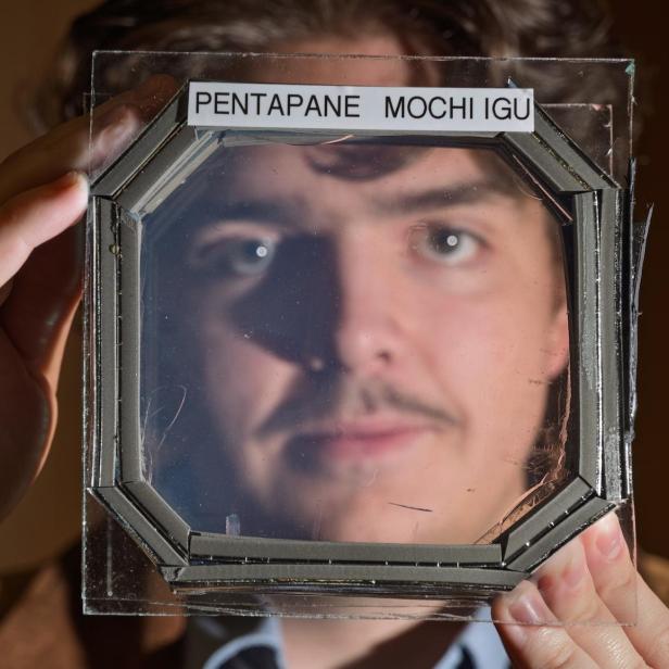 Ein Mann hält eine fast transparente MOCHI-Platte vor sein Gesicht