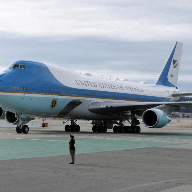 Großes blau-weißes Flugzeug mit der Aufschrift „United States of America“ steht auf dem Rollfeld, eine Person davor.