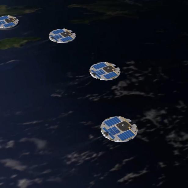 Vier kleine, runde Satelliten mit Solarpanels schweben in Formation über der Erde.
