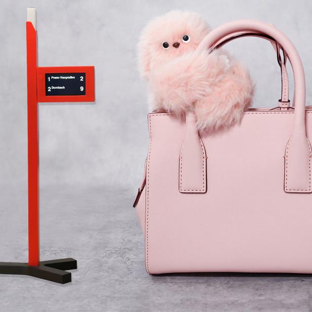 Mini Haltenstellenanzeiger auf grauem Hintergrund neben einer pinken Handtasche