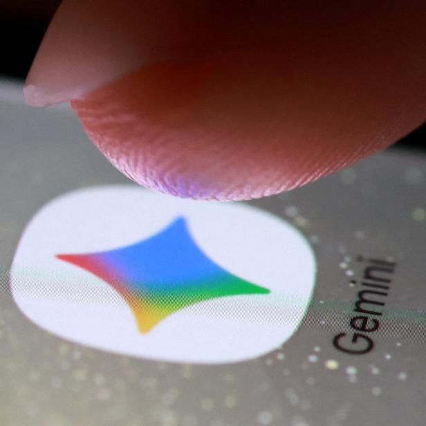 Ein Finger berührt das Symbol einer App mit buntem Stern und der Aufschrift „Gemini“ auf einem Smartphone-Bildschirm.