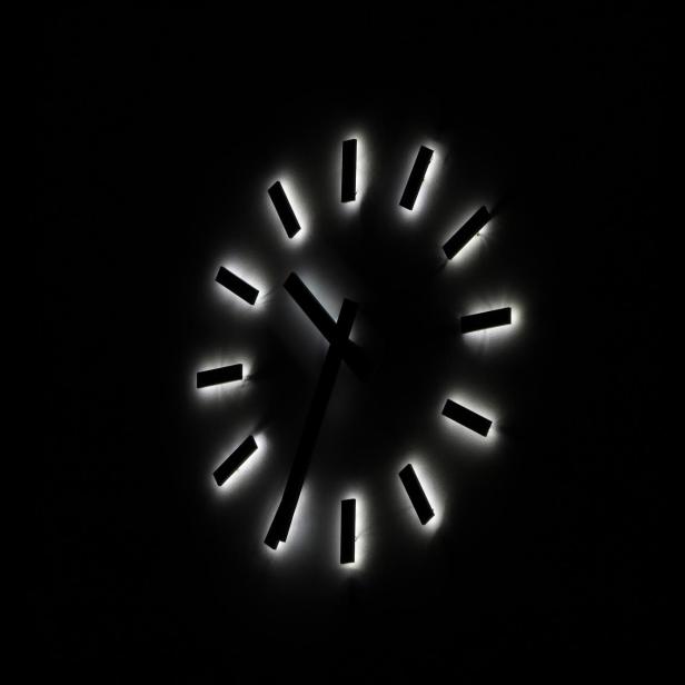 große Wanduhr mit belezchteten Zeigern im Dunkeln