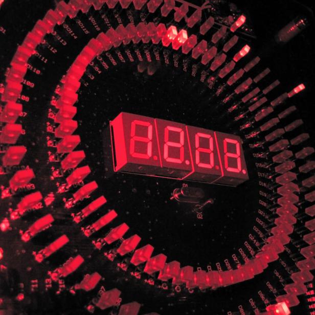 Rotes LED-Display und elektronische Bauteile symbolisieren die technologische Entwicklung hochpräziser Uhren, wie sie für Atomkernuhren erforscht werden.