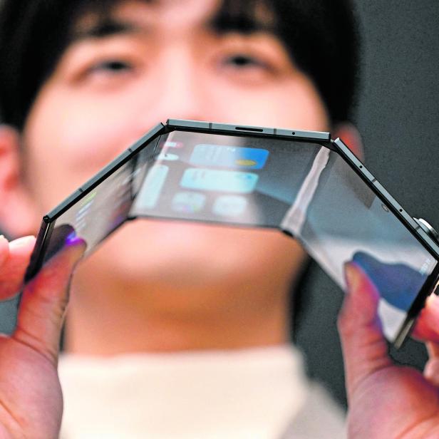 Eine Person hält ein biegsames, mehrfach faltbares Smartphone mit großem Display in beiden Händen.