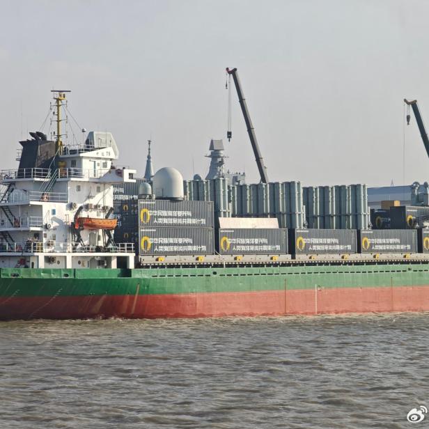 Chinesisches Frachtschiff mit zahlreichen Containern und modularen Raketenwerfern an Deck.