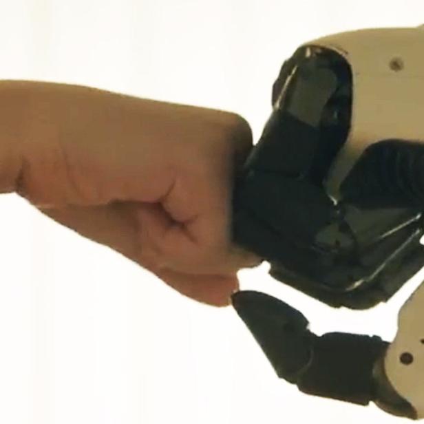 Menschliche Hand macht Fistbump mit Roboterhand
