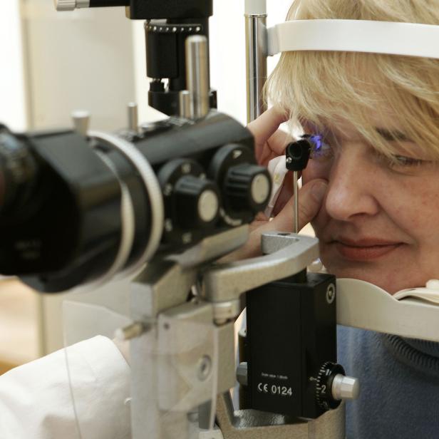 Eine Frau lässt bei einer Augenuntersuchung ihr Auge mit einem Spaltlampenmikroskop prüfen.