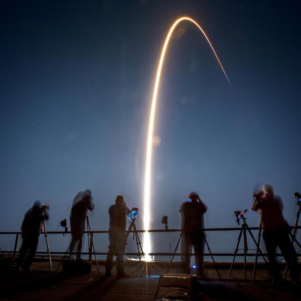 Fotografen beobachten und fotografieren den Start einer Rakete in der Nacht.