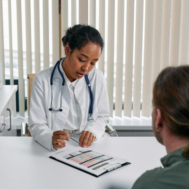 Ärztin bespricht medizinische Testergebnisse mit einem Patienten im Sprechzimmer.