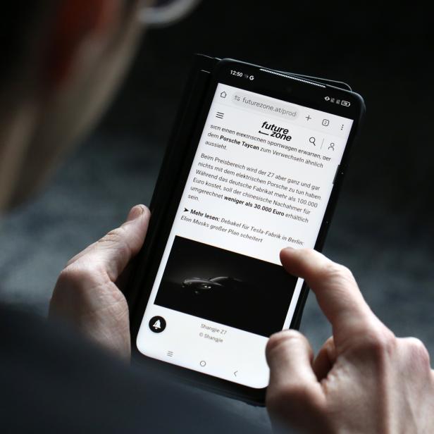 Ein Mann hält das Smartphone TCL Nxtpaper 60 Ultra und liest etwas im ePaper-Modus