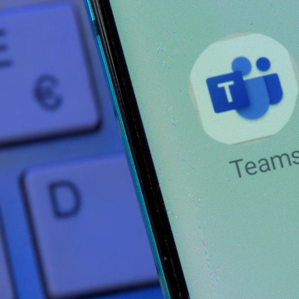 Auf einem Smartphone-Bildschirm ist das Microsoft Teams-Symbol neben einer Computertastatur zu sehen.