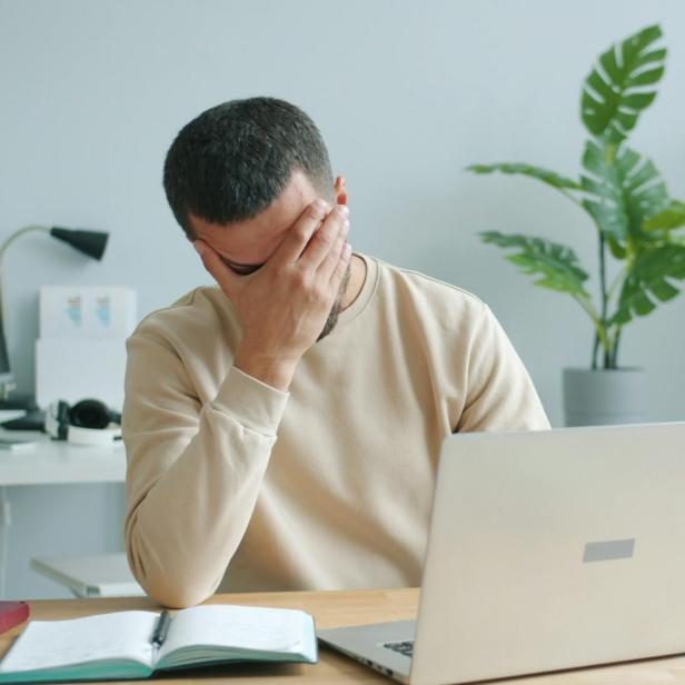 Mann sitzt verzweifelt vor Laptop 