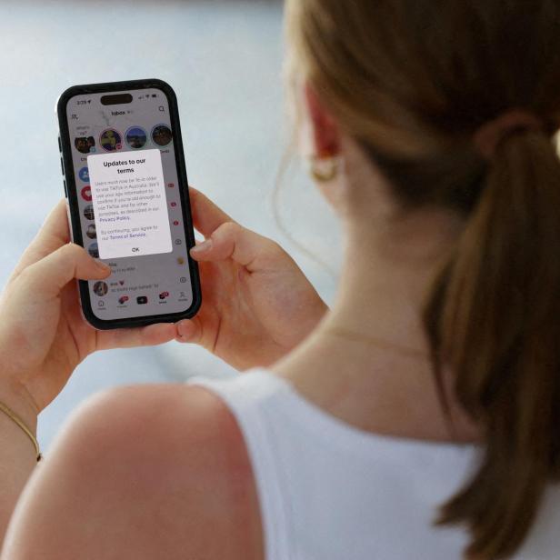 Eine Frau mit Zopf hält ein Smartphone und liest eine Benachrichtigung über aktualisierte Nutzungsbedingungen.