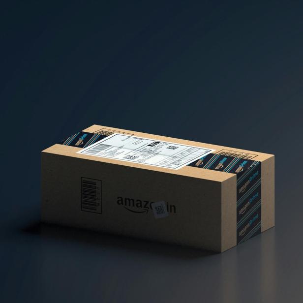 Amazon-Paket mit Prime-Klebeband und Versandetikett auf dunklem Hintergrund.