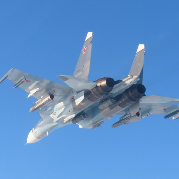 Russischer Kampfjet Su-30SM mit Raketenbewaffnung im Flug vor blauem Himmel.