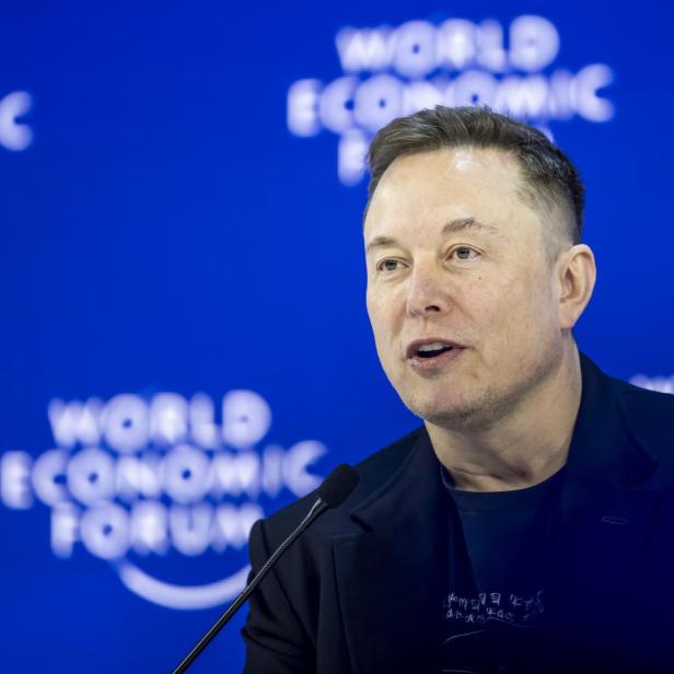 Ein Mann spricht vor einem Mikrofon vor blauem Hintergrund mit der Aufschrift „World Economic Forum“.