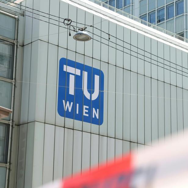 Das Logo der Technischen Universität Wien an einer modernen Gebäudefassade mit einer Straßenlaterne und Stromleitungen.