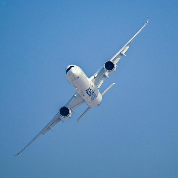 Ein weißes A350-1000 Flugzeug fliegt vor einem wolkenlosen, blauen Himmel.
