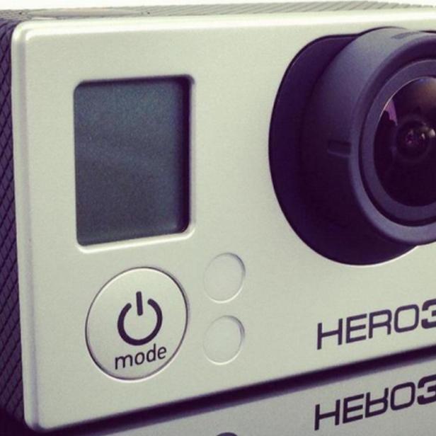 Eine silberne GoPro Hero3 Kamera liegt auf einer glänzenden Oberfläche.