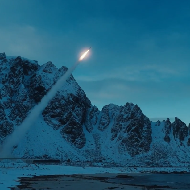Raketenstart vor schneebedeckten Bergen und Küste bei winterlicher Dämmerung.