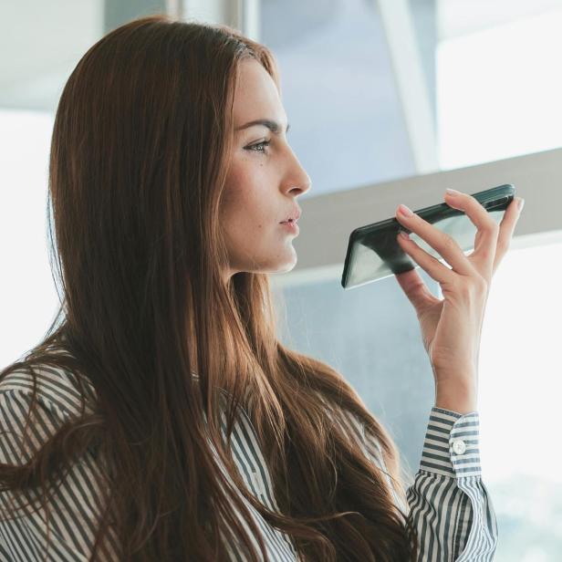 Eine Frau hält ein Handy in der Hand und spricht