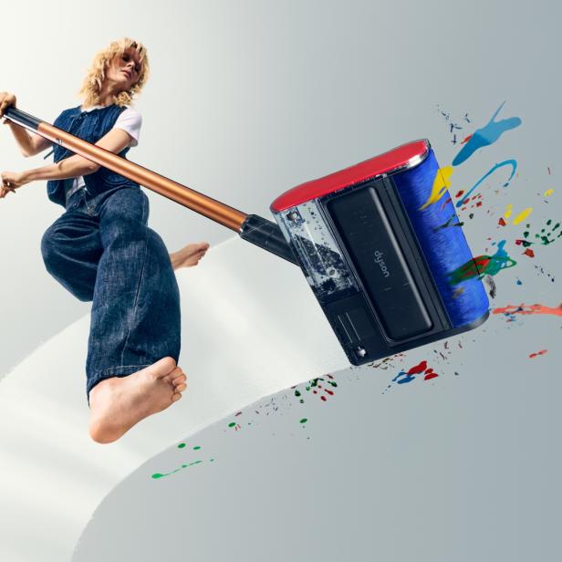 Person wischt mit Dyson PencilWash farbige Flecken auf hellem Boden.