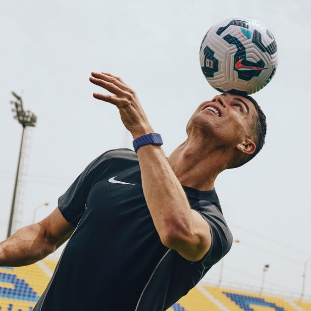 Cristiano Ronaldo mit Fitness-Tracker am Handgelenk köpft Fußball im Stadion.